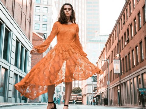 Woman in Orange Long-sleeved Dress Between Buildings During Daytime