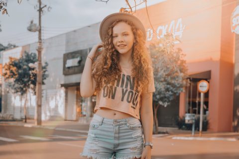 Woman in Crop Top and Denim Shorts Standing Near Storefront