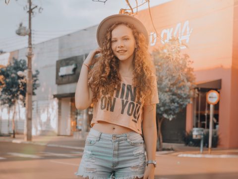 Woman in Crop Top and Denim Shorts Standing Near Storefront
