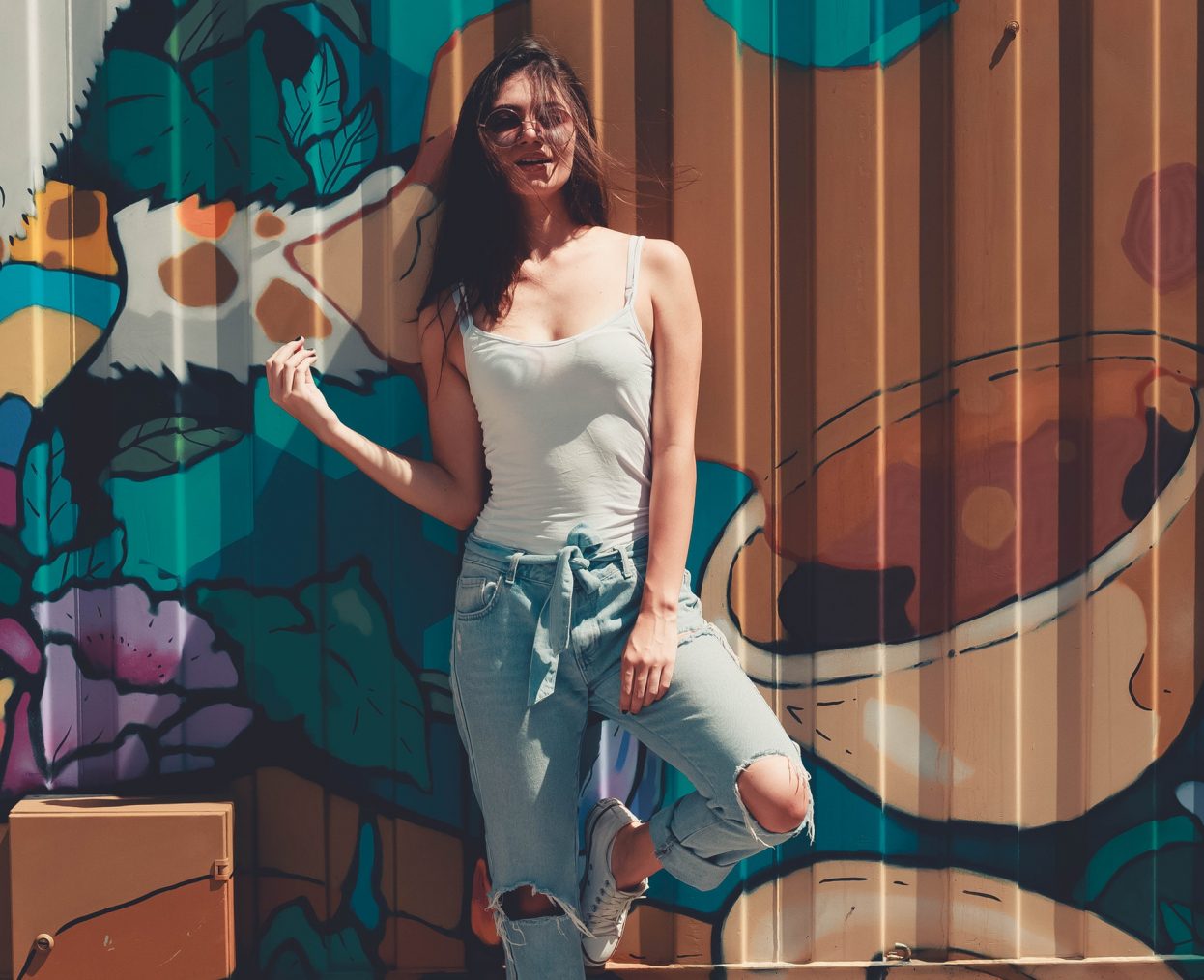 Woman Wearing Gray Tank Top Leaning on Wall With Graffiti
