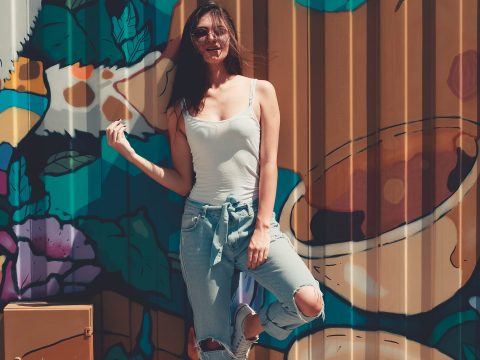 Woman Wearing Gray Tank Top Leaning on Wall With Graffiti