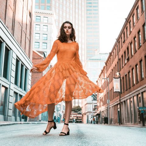Woman in Orange Long-sleeved Dress Between Buildings During Daytime