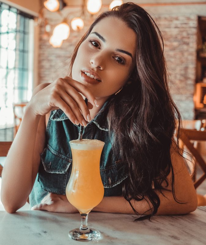 Smiling Woman is Sitting Near Table Holding Straw