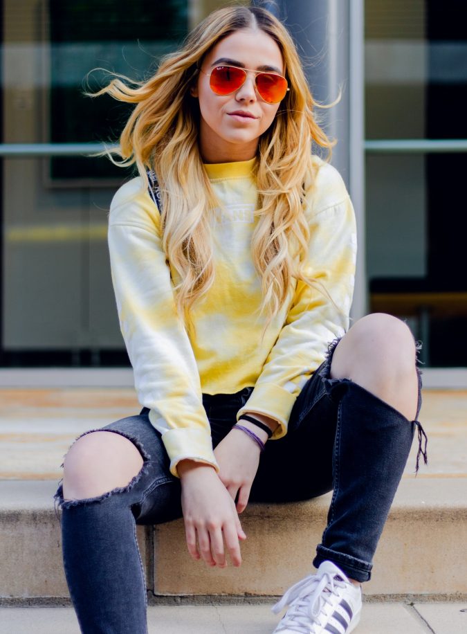 Woman is Sitting on Beige Surface Wearing White and Yellow Long-sleeved Shirt